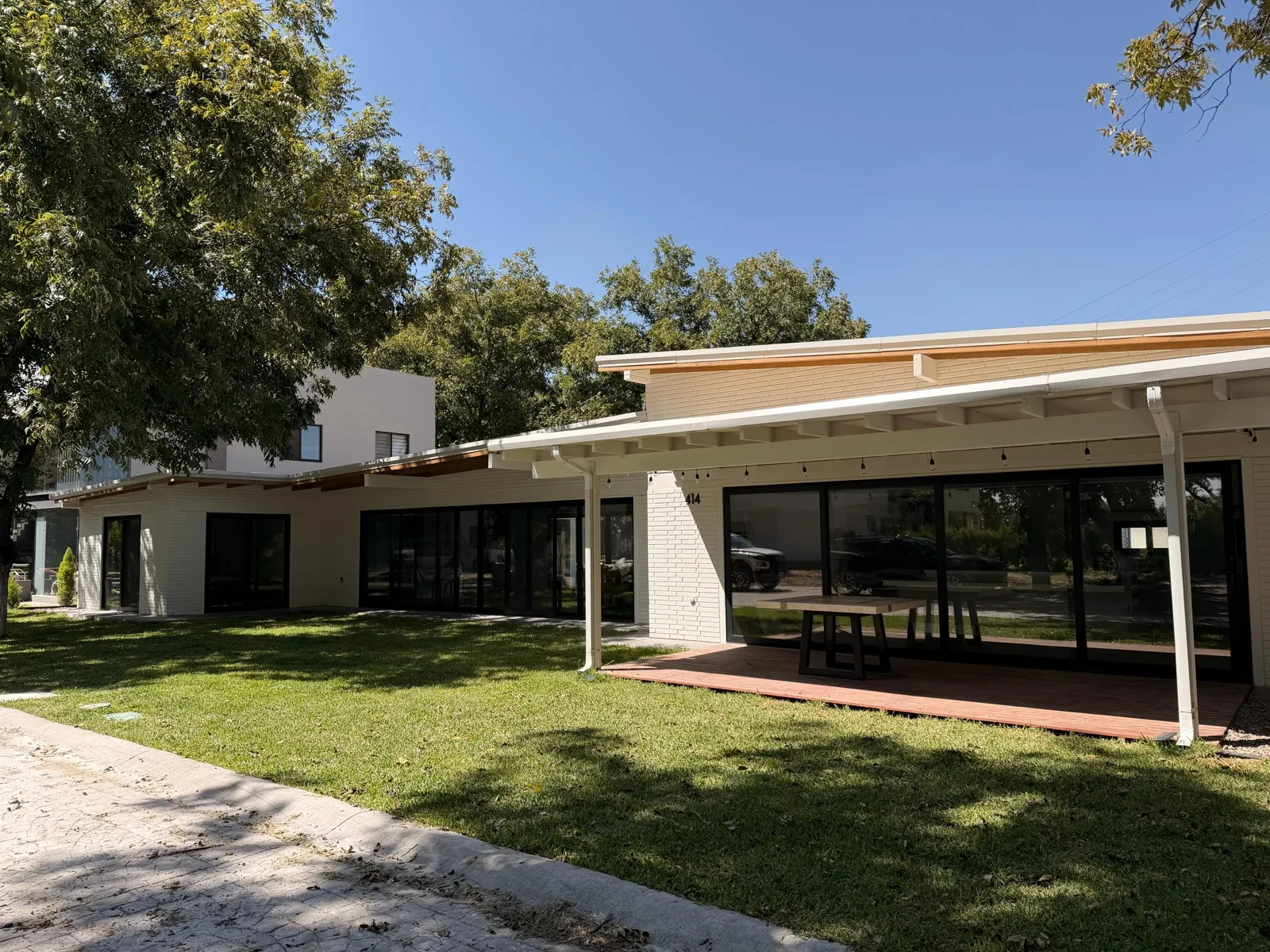 Modern white block home exterior with covered terrace and lawn