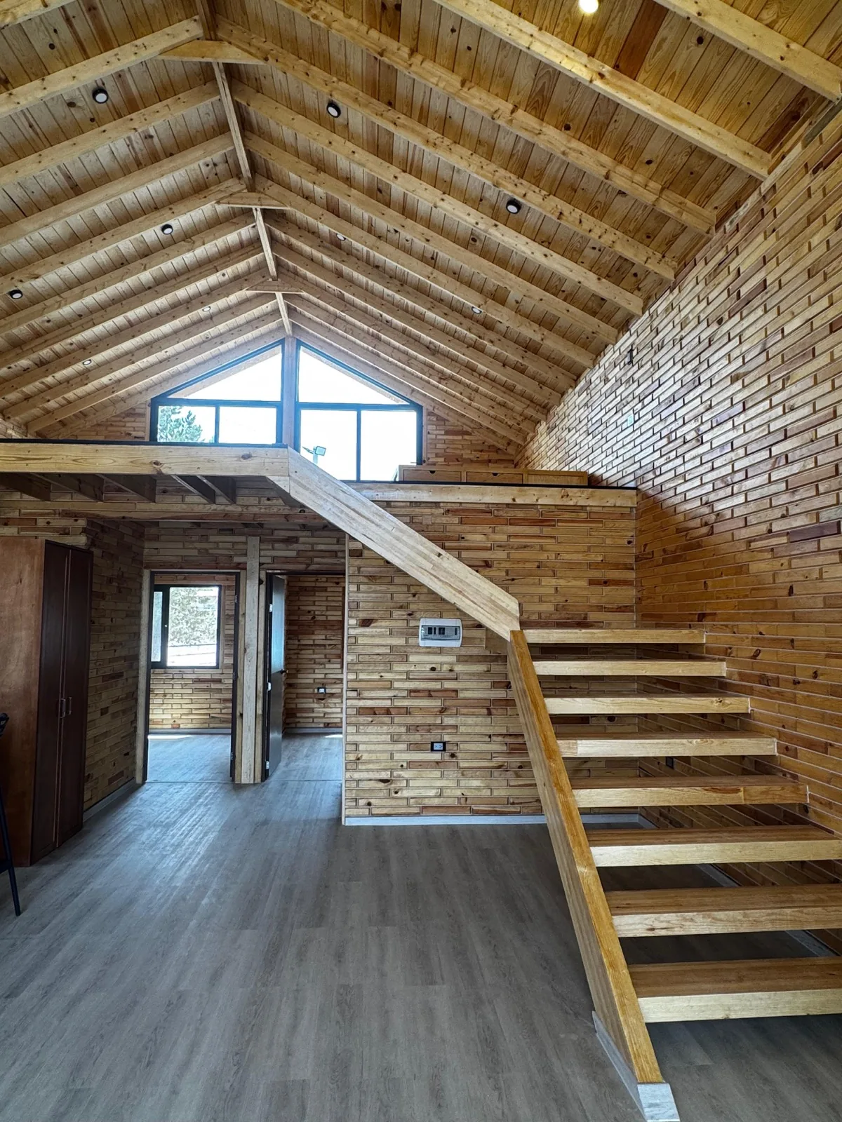 Vaulted natural wood living space with staircase